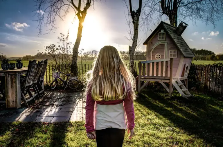 Kind in einem Garten mit Spielhaus