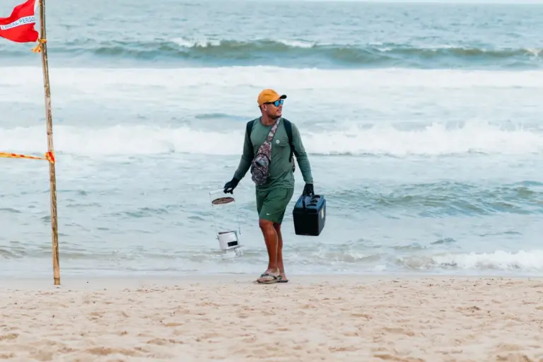 Mann trägt Ausrüstung an einem Sandstrand