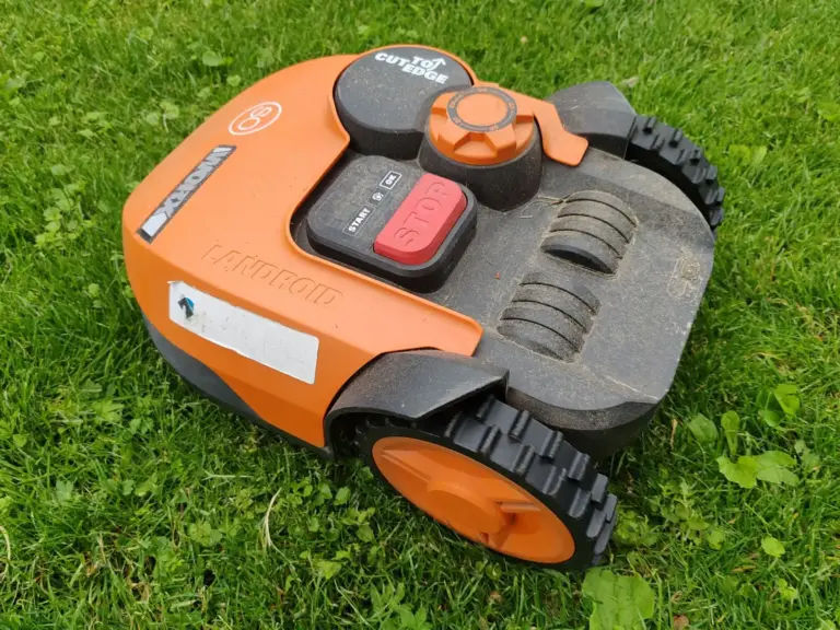 Orangefarbener Mähroboter auf einem Rasen