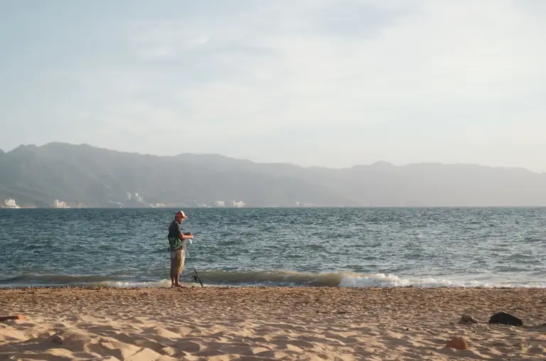 Person am Strand vor einer Bergkulisse