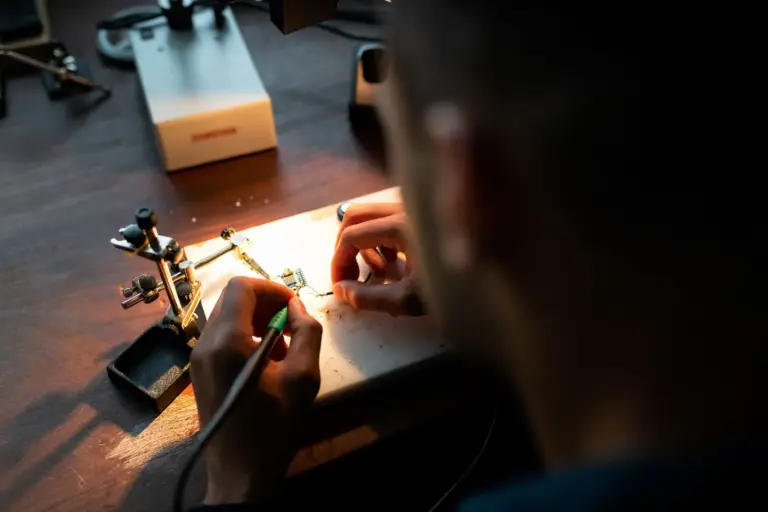 Person lötet eine Platine in einer Werkstatt
