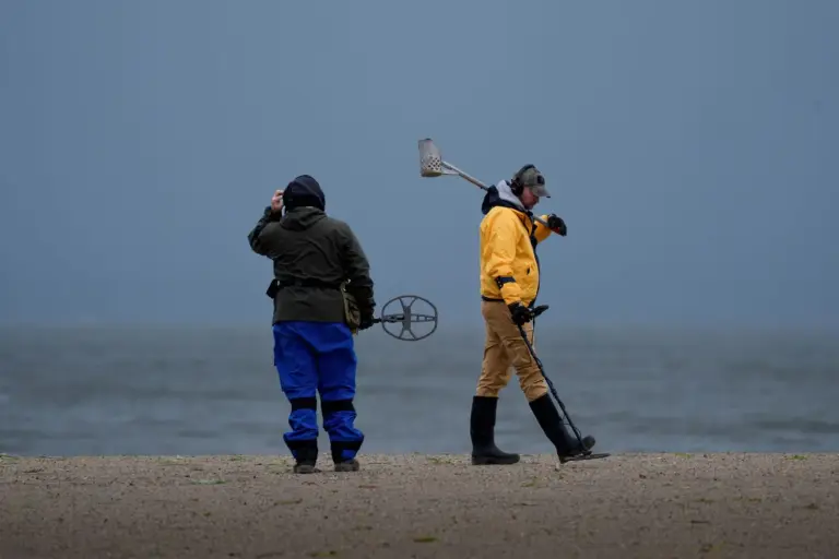 Zwei Sondengänger suchen in der Morgendämmerung am Strand